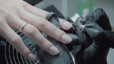 The process of manicure in a beauty salon close-up. Removal of the coating by the device