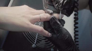 The process of manicure in a beauty salon close-up. Removal of the coating by the device