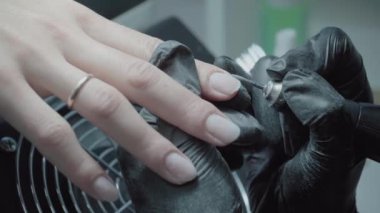 The process of manicure in a beauty salon close-up. Removal of the coating by the device