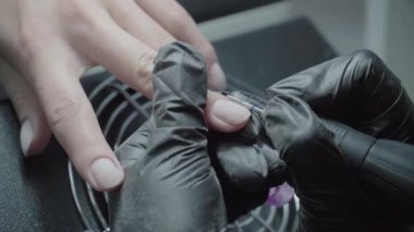 The process of manicure in a beauty salon close-up. Removal of the coating by the device