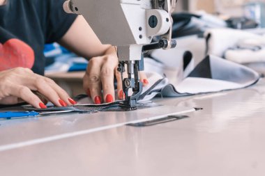 The seamstress sews on an old sewing machine, threads the fabric. Women's hands