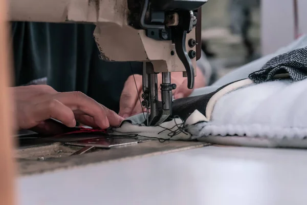 The seamstress sews on an old sewing machine, threads the fabric. Women's hands