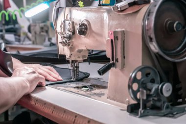 The seamstress sews at the sewing machine, threads the fabric. Women's hands