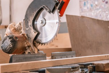 Sawing machine for wood in the workshop for the production of furniture. Woodworking circular saw and wooden bar for cutting.