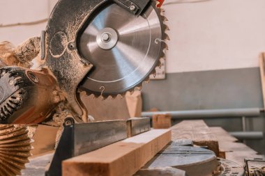 Sawing machine for wood in the workshop for the production of furniture. Woodworking circular saw and wooden bar for cutting.
