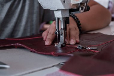 The seamstress sews at the sewing machine, threads the fabric. Women's hands