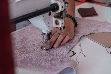 The seamstress sews at the sewing machine, threads the fabric. Women's hands