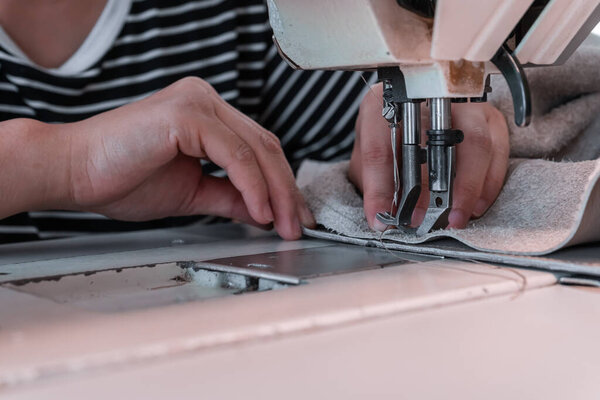 The seamstress sews at the sewing machine, threads the fabric. Women's hands