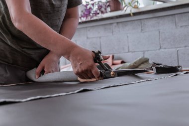 A cutter cuts fabric with scissors in a sewing workshop