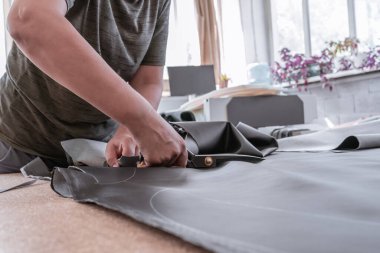 A cutter cuts fabric with scissors in a sewing workshop