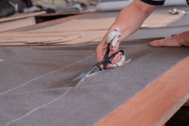 A cutter cuts fabric with scissors in a sewing workshop