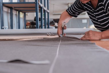 A cutter cuts fabric with scissors in a sewing workshop