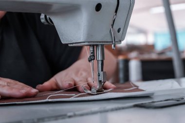 The seamstress sews at the sewing machine, threads the fabric. Women's hands