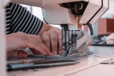 The seamstress sews at the sewing machine, threads the fabric. Women's hands
