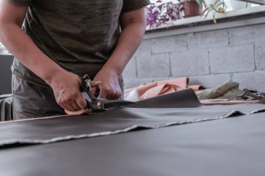 A cutter cuts fabric with scissors in a sewing workshop