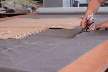 A cutter cuts fabric with scissors in a sewing workshop