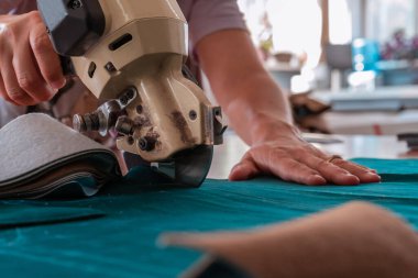 The cutter cuts the fabric with a disc knife in a sewing workshop