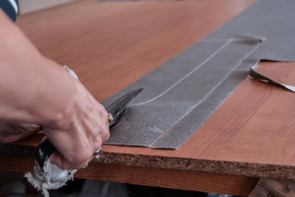 A cutter cuts fabric with scissors in a sewing workshop