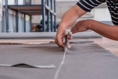 A cutter cuts fabric with scissors in a sewing workshop