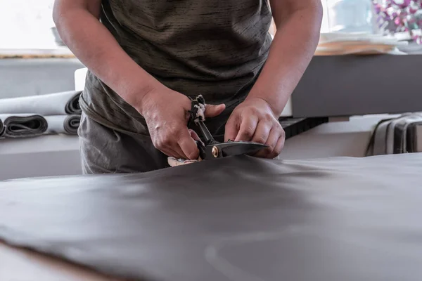 A cutter cuts fabric with scissors in a sewing workshop