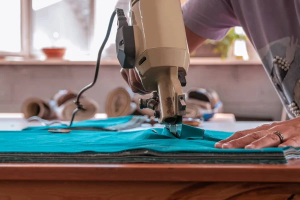 The cutter cuts the fabric with a disc knife in a sewing workshop