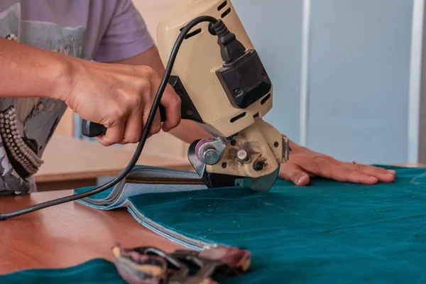 The cutter cuts the fabric with a disc knife in a sewing workshop