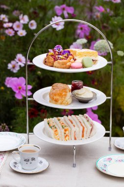 Afternoon tea with cakes, scones and sandwiches clipart