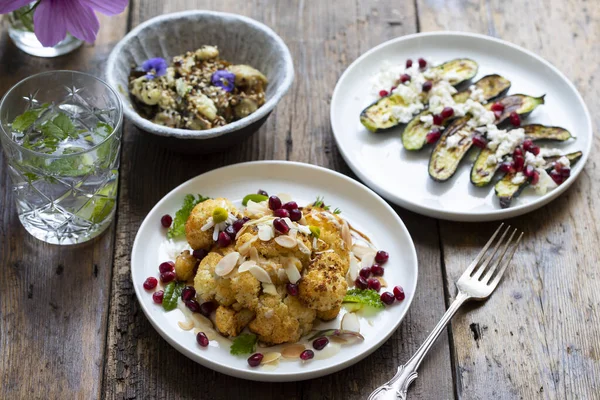 Vegan dishes of miso aubergine, roasted cauliflower and baby courgettes