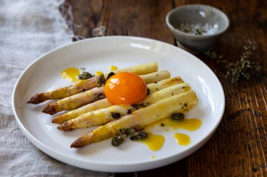 Kapari, hardal sosu ve yumurta sarısı ile kavrulmuş beyaz aspatagus.