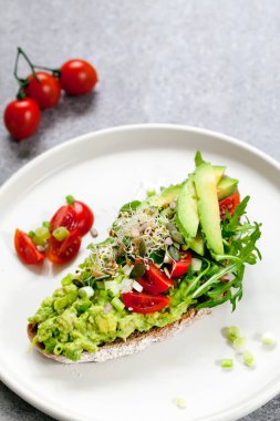 Avokado, domates ve yonca filizli çavdar tostu.