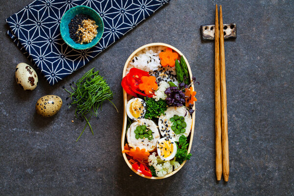 Японский бентобокс с курицей, фаршированной спаржей, рисом, овощами и перепелиными яйцами