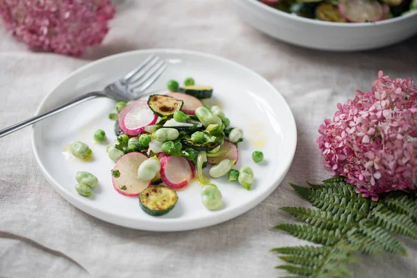 Fresh garden salad with broad beans, green peas, radishes and courgette