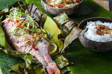 Muz yaprağında pişmiş kırmızı balık, papaya salatası ve pilav.