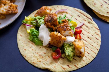 Baharatlı balıklı taco, salata ve ev yapımı guacamole.