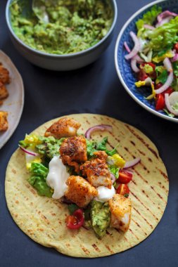 Baharatlı balıklı taco, salata ve ev yapımı guacamole.