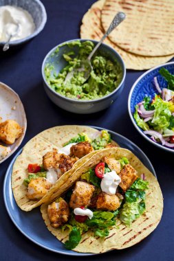 Baharatlı balıklı taco, salata ve ev yapımı guacamole.
