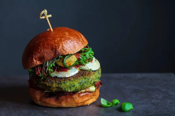 Vegetarian burger made of green pea, butter beans and spinach  with sundried tomato pesto and grilled courgette