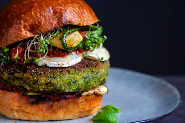 Vegetarian burger made of green pea, butter beans and spinach  with sundried tomato pesto and grilled courgette