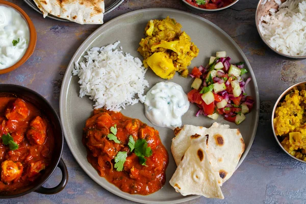 Indian meal with chicken tikka masala, aloo gobi, salad, rice and flat bread