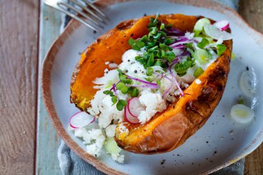 Sweet potato with mashed avocado, yogurt, feta cheese and sprouts