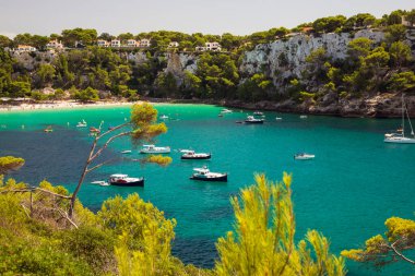 Menorca, İspanya - 1 Eylül 2022: İnsanlar Cala Galdana plajında yüzme ve tekne gezilerinden keyif alıyor