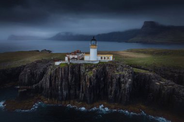 Deniz feneri dağın eteğinde, deniz kenarında, İskoçya