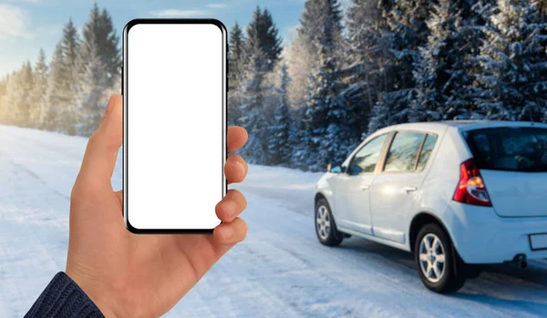 在冬季公路后面的一辆汽车的后面拿着一部电话 空白屏幕 您可以添加内容 — 图库照片