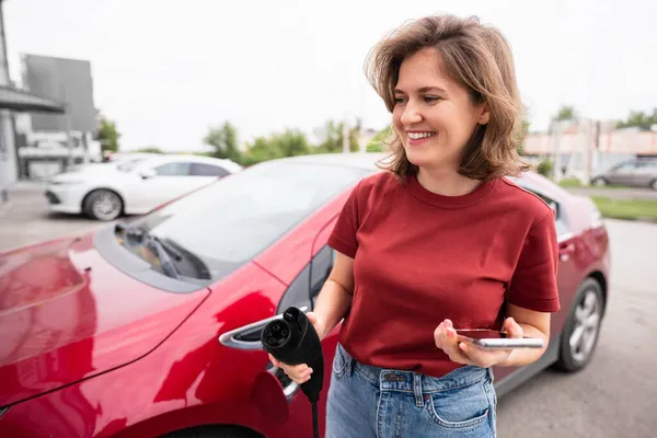 Mulher com smartphone e ficha de carregamento — Fotografia de Stock