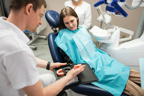 El dentista muestra al paciente un modelo de la mandíbula — Foto de Stock