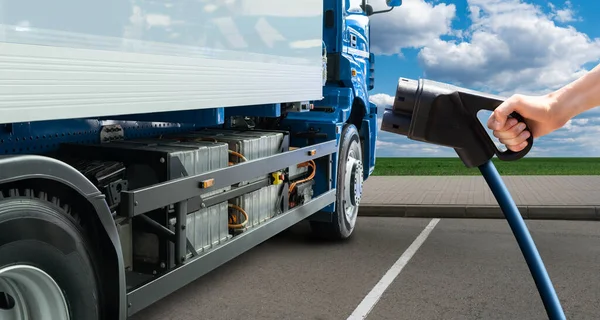 Hand met oplaadplug op een achtergrond van elektrische truck — Stockfoto