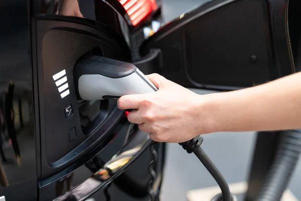 Vrouw met stekker van elektrische auto — Stockfoto