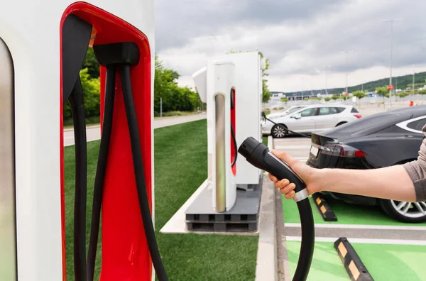 Man holding plug of electric car charging station