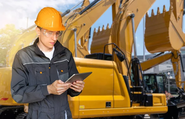 Engineer in a helmet with a digital tablet on the background of construction machines