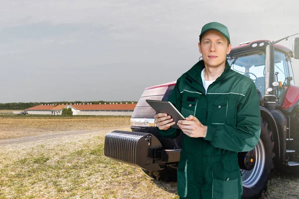 Farmer with a digital tablet on the background of an agricultural tractor